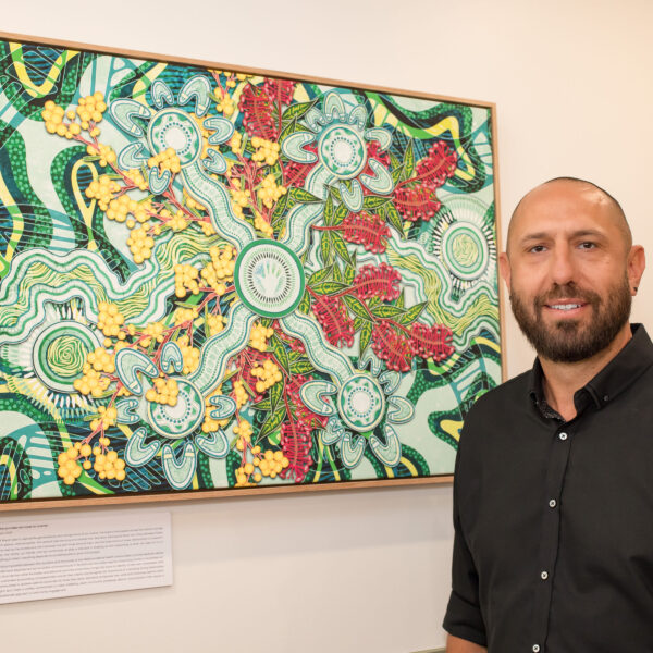 Nathan Peckham in front of his indigenous artwork specifically made for both Dubbo and Bathurst Centres